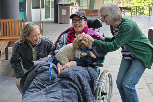 5 West patient Richard and his family receive a visit from Lort Smith Pet Therapy dog Molly and her owner Sophie, in the ONJ Centre Wellness Garden.